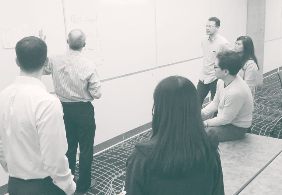 Six people gathered around a white board